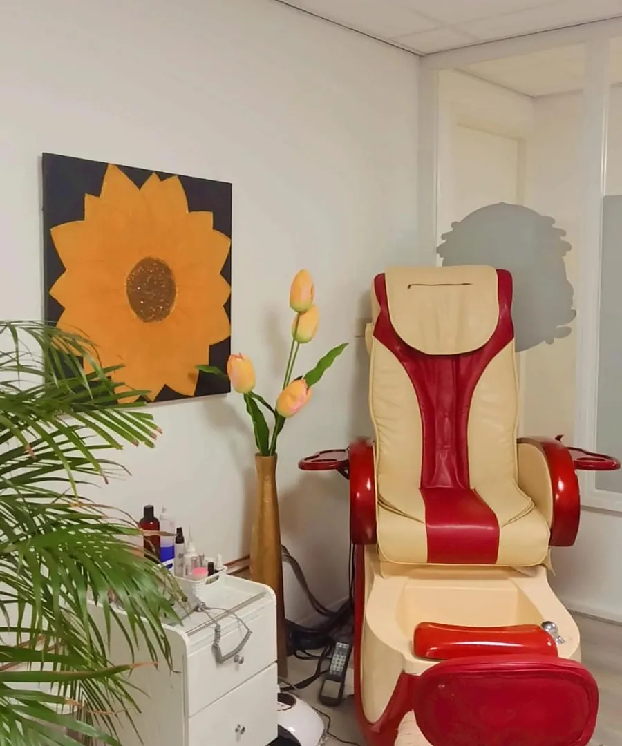 De pedicurestoel in de salon, onder een groot zonnebloemschilderij