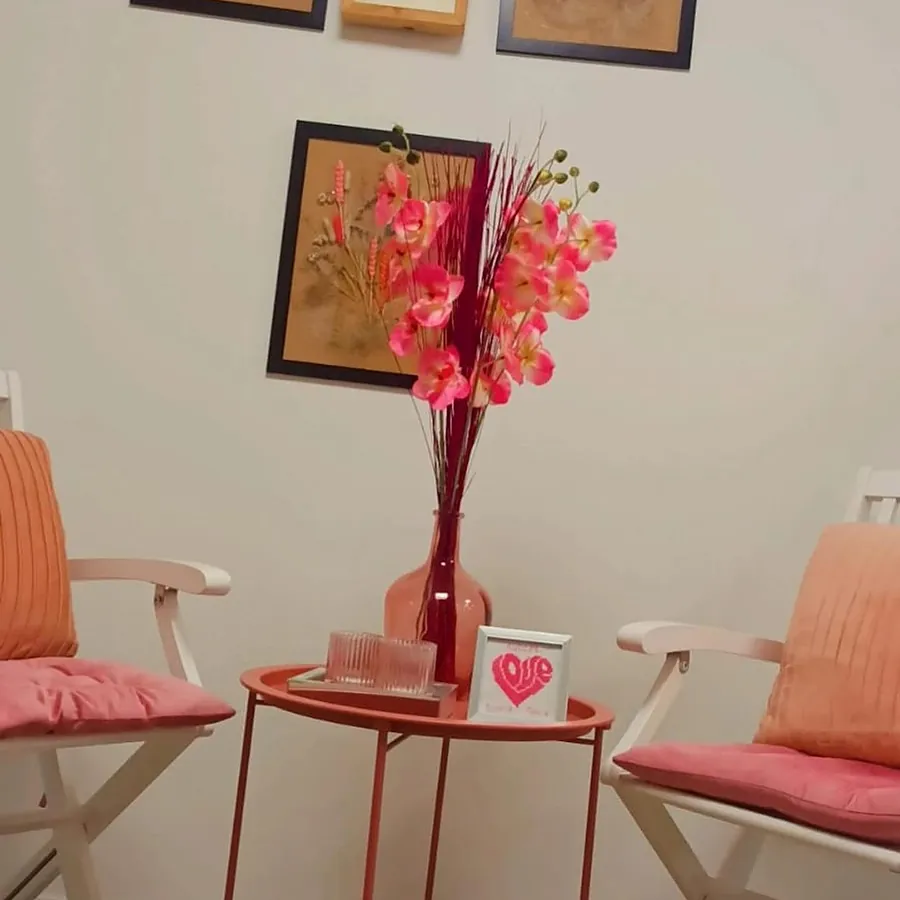 Twee roze stoelen met een rood tafeltje en een orchidee